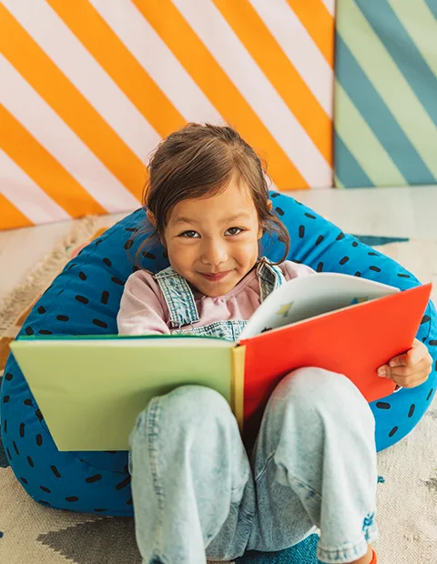 A child smiling while reading a colorful book